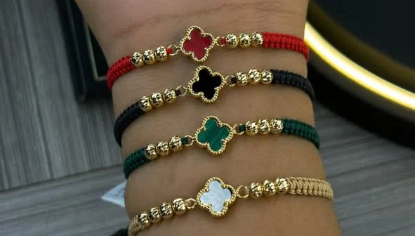 Cuatro pulseras tejidas con trébol de cuatro hojas en rojo, negro, verde y nácar.